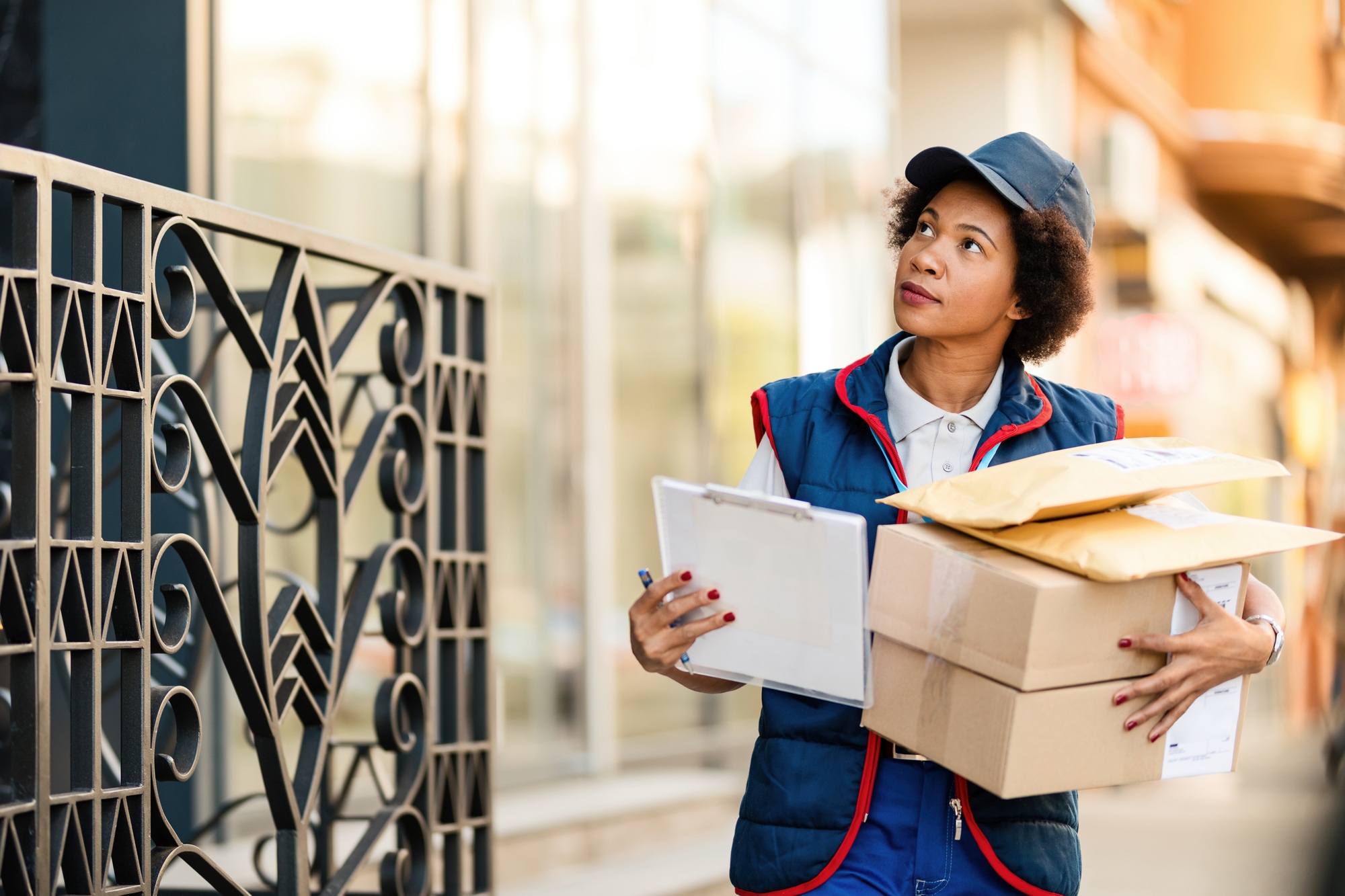 Black female courier looking for a place to deliver the package in the city.