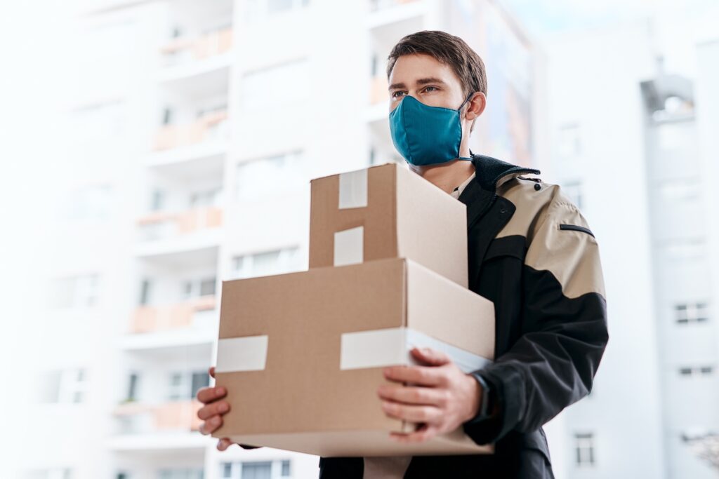 Shot of a masked young man delivering delivering a package to a place of residence